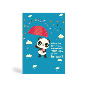A6 blue eco-friendly, tree free, birthday greeting card with Panda standing, holding a present and umbrella. In the background, there is images of clouds and raining presents. The card say, Wishing You Something Unexpectedly Panda-stic on your Birthday!