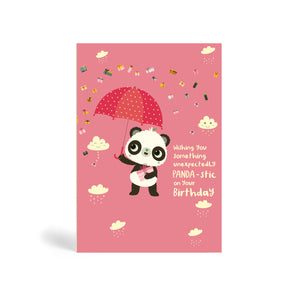 A6 pink eco-friendly, tree free, birthday greeting card with Panda standing, holding a present and umbrella. In the background, there is images of clouds and raining presents. The card say, Wishing You Something Unexpectedly Panda-stic on your Birthday!